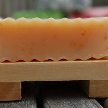 Side view of an unwrapped bar of College Green Lemongrass, Ginger and Oat beer soap next to a wooden soap dish