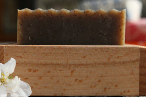 Unwrapped bar of Peppermint & Rosemary Coffee Scrub soap on a wooden soap dish